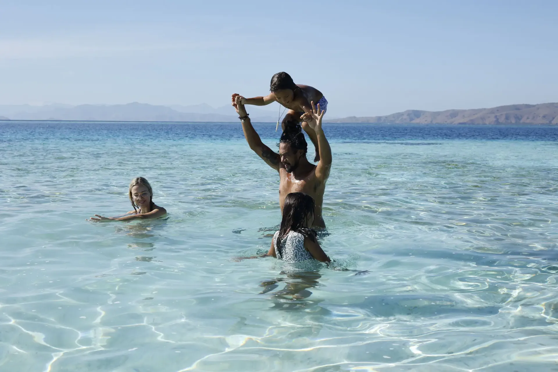 Family playing in crystal clear water Komodo Islands luxury family yacht charter