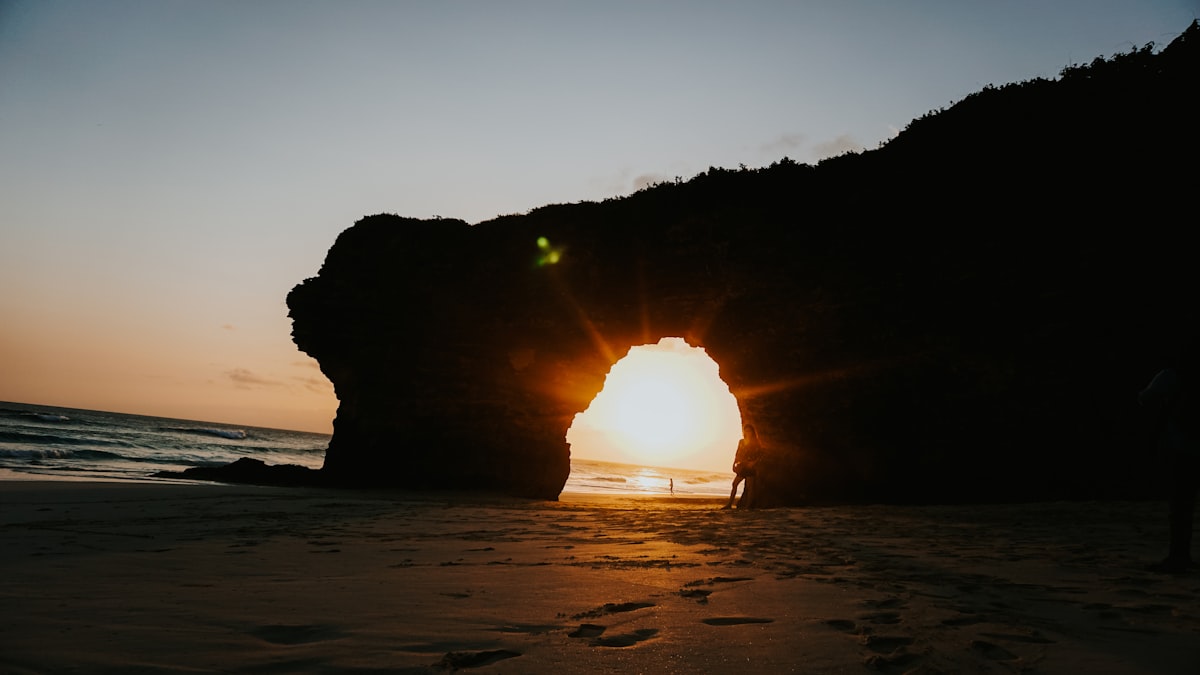Sunset through natural rock archway on Sumbawa beach Indonesia